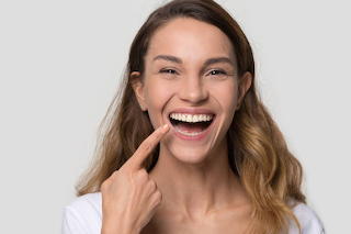 Smiling young woman pointing at her teeth